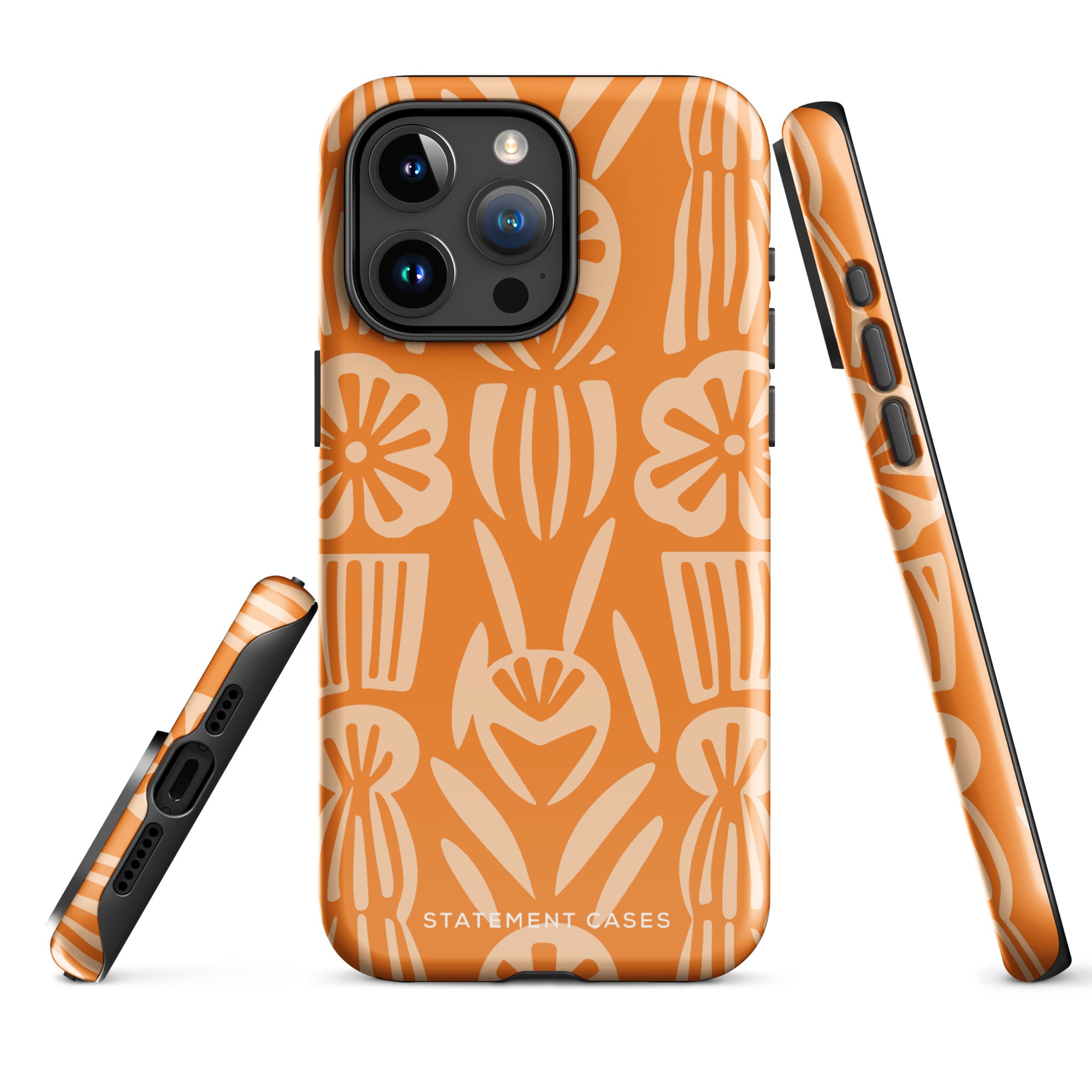 A Savannah Ardiente for iPhone from Statement Cases, featuring a dual-layered phone case in orange with a floral pattern showcasing cream-colored flowers, leaves, and geometric shapes. This impact-resistant polycarbonate case displays "STATEMENT CASES" at the bottom and reveals the camera lenses at the top left corner.