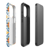 Statement Cases' Mediterranean Bloom for iPhone is showcased, featuring an intricate, colorful pattern. The design includes blue, yellow, and orange floral shapes in a symmetrical arrangement on a light blue background. This durable phone case provides dual-layer protection and is constructed from impact-resistant polycarbonate to safeguard your device.