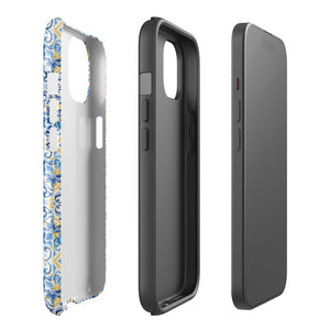 The Blue Mirage for iPhone by Statement Cases features a dual-layered, impact-resistant polycarbonate exterior with a TPU inner liner. Inspired by traditional Portuguese tiles, the blue and yellow patterned case boasts an intricate design of floral and geometric motifs. With its elegant and colorful appearance, the phone's camera is visible at the top left of the case.