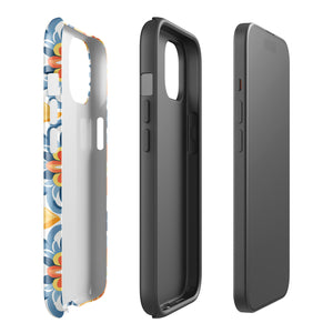 Statement Cases' Mediterranean Bloom for iPhone is showcased, featuring an intricate, colorful pattern. The design includes blue, yellow, and orange floral shapes in a symmetrical arrangement on a light blue background. This durable phone case provides dual-layer protection and is constructed from impact-resistant polycarbonate to safeguard your device.