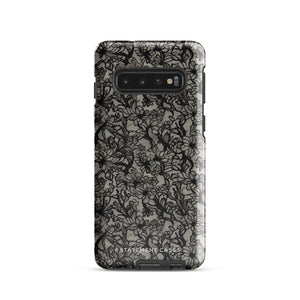 A phone case with a protective dual-layer design featuring an intricate black floral lace pattern. The Omerta Floral for Samsung has four camera cutouts and the brand name "Statement Cases" appears at the bottom center. Impact-resistant and chic, it stands against a plain white background.