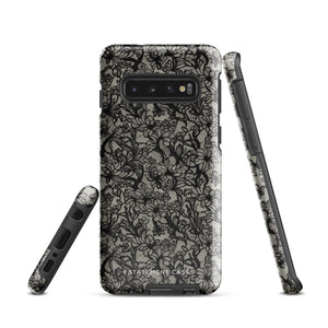 A phone case with a protective dual-layer design featuring an intricate black floral lace pattern. The Omerta Floral for Samsung has four camera cutouts and the brand name "Statement Cases" appears at the bottom center. Impact-resistant and chic, it stands against a plain white background.