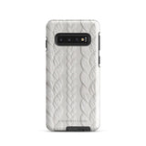 A stylish, impact-resistant phone case with a textured white braided design, covering the back of a smartphone. The dual-layer design features cutouts for the camera and buttons, and "Cozy Knit Bliss for Samsung" by Statement Cases is embossed at the bottom.