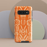 This stylish smartphone accessory, the Savannah Ardiente for Samsung by Statement Cases, features a shock-absorbing, colorful patterned case adorned with abstract flower designs in beige on an orange background. This impact-resistant phone case wraps around the back of your device, providing robust protection for its multiple camera lenses in the corner.