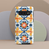 The Mediterranean Bloom for Samsung by Statement Cases features intricate, colorful floral patterns in blue, orange, and yellow. The design covers the entire back of the case, surrounding the camera cutout. Shock-absorbing and impact-resistant, it ensures protection while the brand "Statement Cases" is subtly printed near the bottom.