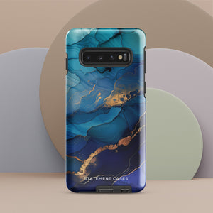 A Samsung smartphone adorned with the Midnight Wave Marble—a vibrant, blue and gold marble-patterned dual-layer phone case. Featuring multiple camera lenses at the top left corner, this impact-resistant case is elegantly labeled "Statement Cases" in white text at the bottom. The design showcases fluid, swirling layers with metallic accents.