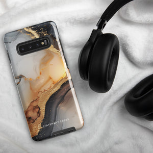 A smartphone with a dual-layer design case featuring a black and gold marbled pattern. The camera array with multiple lenses is visible on the top left corner of the phone. The tough-yet-sleek phone case, Lunar & Gold Marble for Samsung, proudly displays the text "Statement Cases" at the bottom center.