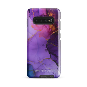 The Golden Orchid Marble for Samsung by Statement Cases is a smartphone adorned with a vibrant, abstract phone case showcasing a mix of purple, pink, and gold colors. Crafted from impact-resistant materials, it features a camera module with four lenses and a flash. At the bottom of the shock-absorbing phone case, you’ll find the text "STATEMENT CASES" in white.