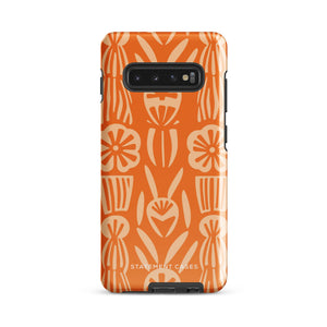 This stylish smartphone accessory, the Savannah Ardiente for Samsung by Statement Cases, features a shock-absorbing, colorful patterned case adorned with abstract flower designs in beige on an orange background. This impact-resistant phone case wraps around the back of your device, providing robust protection for its multiple camera lenses in the corner.