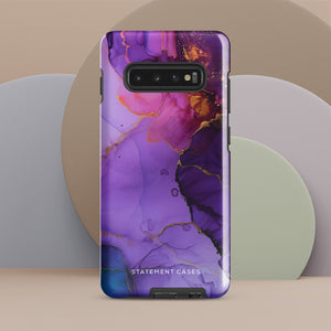 The Golden Orchid Marble for Samsung by Statement Cases is a smartphone adorned with a vibrant, abstract phone case showcasing a mix of purple, pink, and gold colors. Crafted from impact-resistant materials, it features a camera module with four lenses and a flash. At the bottom of the shock-absorbing phone case, you’ll find the text "STATEMENT CASES" in white.