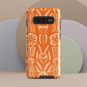 This stylish smartphone accessory, the Savannah Ardiente for Samsung by Statement Cases, features a shock-absorbing, colorful patterned case adorned with abstract flower designs in beige on an orange background. This impact-resistant phone case wraps around the back of your device, providing robust protection for its multiple camera lenses in the corner.