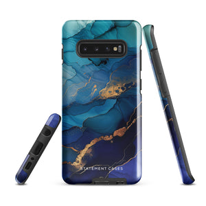 A Samsung smartphone adorned with the Midnight Wave Marble—a vibrant, blue and gold marble-patterned dual-layer phone case. Featuring multiple camera lenses at the top left corner, this impact-resistant case is elegantly labeled "Statement Cases" in white text at the bottom. The design showcases fluid, swirling layers with metallic accents.