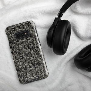 A phone case with a protective dual-layer design featuring an intricate black floral lace pattern. The Omerta Floral for Samsung has four camera cutouts and the brand name "Statement Cases" appears at the bottom center. Impact-resistant and chic, it stands against a plain white background.