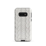 A stylish, impact-resistant phone case with a textured white braided design, covering the back of a smartphone. The dual-layer design features cutouts for the camera and buttons, and "Cozy Knit Bliss for Samsung" by Statement Cases is embossed at the bottom.