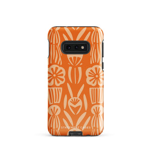 This stylish smartphone accessory, the Savannah Ardiente for Samsung by Statement Cases, features a shock-absorbing, colorful patterned case adorned with abstract flower designs in beige on an orange background. This impact-resistant phone case wraps around the back of your device, providing robust protection for its multiple camera lenses in the corner.