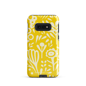 The Sol Dorado for Samsung by Statement Cases is a durable phone case featuring a bright yellow background adorned with an abstract white floral pattern, showcasing various flowers and leaves. Near the bottom edge, the text "STATEMENT CASE" highlights its dual-layer design for enhanced durability.