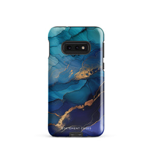 A Samsung smartphone adorned with the Midnight Wave Marble—a vibrant, blue and gold marble-patterned dual-layer phone case. Featuring multiple camera lenses at the top left corner, this impact-resistant case is elegantly labeled "Statement Cases" in white text at the bottom. The design showcases fluid, swirling layers with metallic accents.