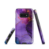 The Golden Orchid Marble for Samsung by Statement Cases is a smartphone adorned with a vibrant, abstract phone case showcasing a mix of purple, pink, and gold colors. Crafted from impact-resistant materials, it features a camera module with four lenses and a flash. At the bottom of the shock-absorbing phone case, you’ll find the text "STATEMENT CASES" in white.