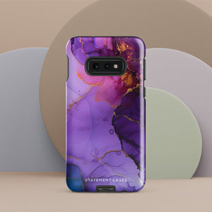 The Golden Orchid Marble for Samsung by Statement Cases is a smartphone adorned with a vibrant, abstract phone case showcasing a mix of purple, pink, and gold colors. Crafted from impact-resistant materials, it features a camera module with four lenses and a flash. At the bottom of the shock-absorbing phone case, you’ll find the text "STATEMENT CASES" in white.