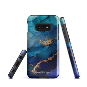 A Samsung smartphone adorned with the Midnight Wave Marble—a vibrant, blue and gold marble-patterned dual-layer phone case. Featuring multiple camera lenses at the top left corner, this impact-resistant case is elegantly labeled "Statement Cases" in white text at the bottom. The design showcases fluid, swirling layers with metallic accents.