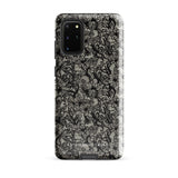 A phone case with a protective dual-layer design featuring an intricate black floral lace pattern. The Omerta Floral for Samsung has four camera cutouts and the brand name "Statement Cases" appears at the bottom center. Impact-resistant and chic, it stands against a plain white background.