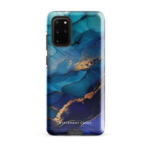 A Samsung smartphone adorned with the Midnight Wave Marble—a vibrant, blue and gold marble-patterned dual-layer phone case. Featuring multiple camera lenses at the top left corner, this impact-resistant case is elegantly labeled "Statement Cases" in white text at the bottom. The design showcases fluid, swirling layers with metallic accents.