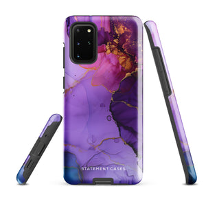 The Golden Orchid Marble for Samsung by Statement Cases is a smartphone adorned with a vibrant, abstract phone case showcasing a mix of purple, pink, and gold colors. Crafted from impact-resistant materials, it features a camera module with four lenses and a flash. At the bottom of the shock-absorbing phone case, you’ll find the text "STATEMENT CASES" in white.