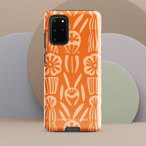 This stylish smartphone accessory, the Savannah Ardiente for Samsung by Statement Cases, features a shock-absorbing, colorful patterned case adorned with abstract flower designs in beige on an orange background. This impact-resistant phone case wraps around the back of your device, providing robust protection for its multiple camera lenses in the corner.