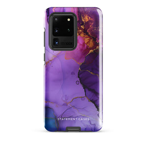 The Golden Orchid Marble for Samsung by Statement Cases is a smartphone adorned with a vibrant, abstract phone case showcasing a mix of purple, pink, and gold colors. Crafted from impact-resistant materials, it features a camera module with four lenses and a flash. At the bottom of the shock-absorbing phone case, you’ll find the text "STATEMENT CASES" in white.