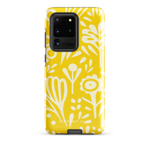 The Sol Dorado for Samsung by Statement Cases is a durable phone case featuring a bright yellow background adorned with an abstract white floral pattern, showcasing various flowers and leaves. Near the bottom edge, the text "STATEMENT CASE" highlights its dual-layer design for enhanced durability.