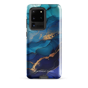 A Samsung smartphone adorned with the Midnight Wave Marble—a vibrant, blue and gold marble-patterned dual-layer phone case. Featuring multiple camera lenses at the top left corner, this impact-resistant case is elegantly labeled "Statement Cases" in white text at the bottom. The design showcases fluid, swirling layers with metallic accents.