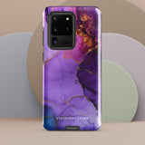 The Golden Orchid Marble for Samsung by Statement Cases is a smartphone adorned with a vibrant, abstract phone case showcasing a mix of purple, pink, and gold colors. Crafted from impact-resistant materials, it features a camera module with four lenses and a flash. At the bottom of the shock-absorbing phone case, you’ll find the text "STATEMENT CASES" in white.