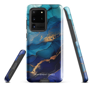 A Samsung smartphone adorned with the Midnight Wave Marble—a vibrant, blue and gold marble-patterned dual-layer phone case. Featuring multiple camera lenses at the top left corner, this impact-resistant case is elegantly labeled "Statement Cases" in white text at the bottom. The design showcases fluid, swirling layers with metallic accents.