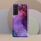 The Golden Orchid Marble for Samsung by Statement Cases is a smartphone adorned with a vibrant, abstract phone case showcasing a mix of purple, pink, and gold colors. Crafted from impact-resistant materials, it features a camera module with four lenses and a flash. At the bottom of the shock-absorbing phone case, you’ll find the text "STATEMENT CASES" in white.