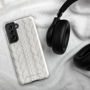 A stylish, impact-resistant phone case with a textured white braided design, covering the back of a smartphone. The dual-layer design features cutouts for the camera and buttons, and "Cozy Knit Bliss for Samsung" by Statement Cases is embossed at the bottom.