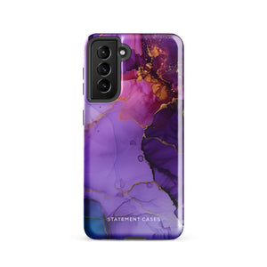 The Golden Orchid Marble for Samsung by Statement Cases is a smartphone adorned with a vibrant, abstract phone case showcasing a mix of purple, pink, and gold colors. Crafted from impact-resistant materials, it features a camera module with four lenses and a flash. At the bottom of the shock-absorbing phone case, you’ll find the text "STATEMENT CASES" in white.