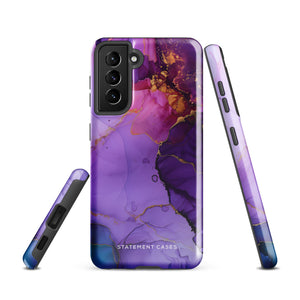 The Golden Orchid Marble for Samsung by Statement Cases is a smartphone adorned with a vibrant, abstract phone case showcasing a mix of purple, pink, and gold colors. Crafted from impact-resistant materials, it features a camera module with four lenses and a flash. At the bottom of the shock-absorbing phone case, you’ll find the text "STATEMENT CASES" in white.