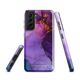 The Golden Orchid Marble for Samsung by Statement Cases is a smartphone adorned with a vibrant, abstract phone case showcasing a mix of purple, pink, and gold colors. Crafted from impact-resistant materials, it features a camera module with four lenses and a flash. At the bottom of the shock-absorbing phone case, you’ll find the text "STATEMENT CASES" in white.