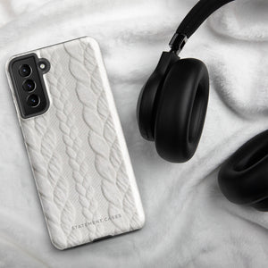 A stylish, impact-resistant phone case with a textured white braided design, covering the back of a smartphone. The dual-layer design features cutouts for the camera and buttons, and "Cozy Knit Bliss for Samsung" by Statement Cases is embossed at the bottom.