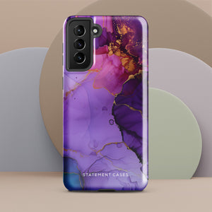 The Golden Orchid Marble for Samsung by Statement Cases is a smartphone adorned with a vibrant, abstract phone case showcasing a mix of purple, pink, and gold colors. Crafted from impact-resistant materials, it features a camera module with four lenses and a flash. At the bottom of the shock-absorbing phone case, you’ll find the text "STATEMENT CASES" in white.