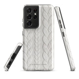 A stylish, impact-resistant phone case with a textured white braided design, covering the back of a smartphone. The dual-layer design features cutouts for the camera and buttons, and "Cozy Knit Bliss for Samsung" by Statement Cases is embossed at the bottom.