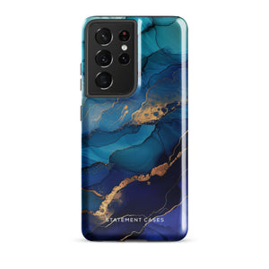 A Samsung smartphone adorned with the Midnight Wave Marble—a vibrant, blue and gold marble-patterned dual-layer phone case. Featuring multiple camera lenses at the top left corner, this impact-resistant case is elegantly labeled "Statement Cases" in white text at the bottom. The design showcases fluid, swirling layers with metallic accents.