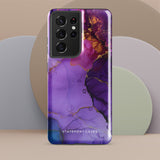 The Golden Orchid Marble for Samsung by Statement Cases is a smartphone adorned with a vibrant, abstract phone case showcasing a mix of purple, pink, and gold colors. Crafted from impact-resistant materials, it features a camera module with four lenses and a flash. At the bottom of the shock-absorbing phone case, you’ll find the text "STATEMENT CASES" in white.