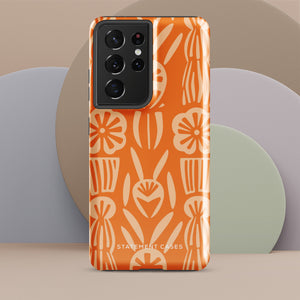 This stylish smartphone accessory, the Savannah Ardiente for Samsung by Statement Cases, features a shock-absorbing, colorful patterned case adorned with abstract flower designs in beige on an orange background. This impact-resistant phone case wraps around the back of your device, providing robust protection for its multiple camera lenses in the corner.