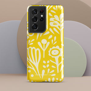 The Sol Dorado for Samsung by Statement Cases is a durable phone case featuring a bright yellow background adorned with an abstract white floral pattern, showcasing various flowers and leaves. Near the bottom edge, the text "STATEMENT CASE" highlights its dual-layer design for enhanced durability.