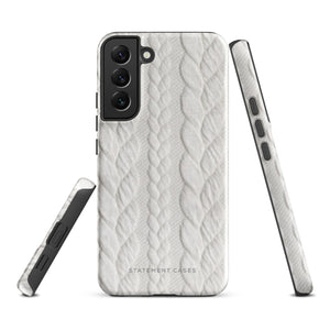 A stylish, impact-resistant phone case with a textured white braided design, covering the back of a smartphone. The dual-layer design features cutouts for the camera and buttons, and "Cozy Knit Bliss for Samsung" by Statement Cases is embossed at the bottom.