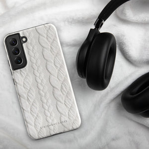 A stylish, impact-resistant phone case with a textured white braided design, covering the back of a smartphone. The dual-layer design features cutouts for the camera and buttons, and "Cozy Knit Bliss for Samsung" by Statement Cases is embossed at the bottom.