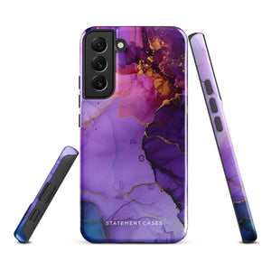 The Golden Orchid Marble for Samsung by Statement Cases is a smartphone adorned with a vibrant, abstract phone case showcasing a mix of purple, pink, and gold colors. Crafted from impact-resistant materials, it features a camera module with four lenses and a flash. At the bottom of the shock-absorbing phone case, you’ll find the text "STATEMENT CASES" in white.