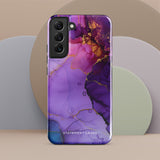 The Golden Orchid Marble for Samsung by Statement Cases is a smartphone adorned with a vibrant, abstract phone case showcasing a mix of purple, pink, and gold colors. Crafted from impact-resistant materials, it features a camera module with four lenses and a flash. At the bottom of the shock-absorbing phone case, you’ll find the text "STATEMENT CASES" in white.