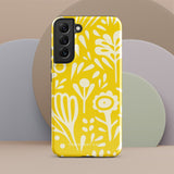 The Sol Dorado for Samsung by Statement Cases is a durable phone case featuring a bright yellow background adorned with an abstract white floral pattern, showcasing various flowers and leaves. Near the bottom edge, the text "STATEMENT CASE" highlights its dual-layer design for enhanced durability.